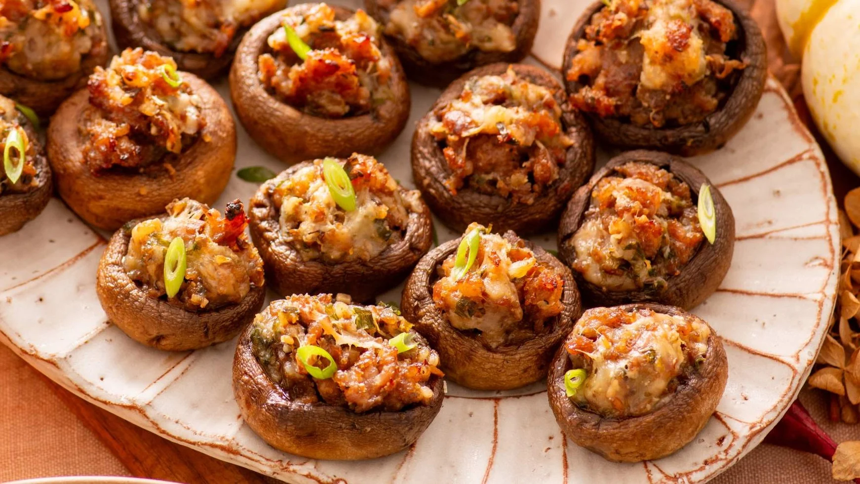 Stuffed mushroom caps filled with savory mixture topped with green onions, arranged on a white ceramic plate.