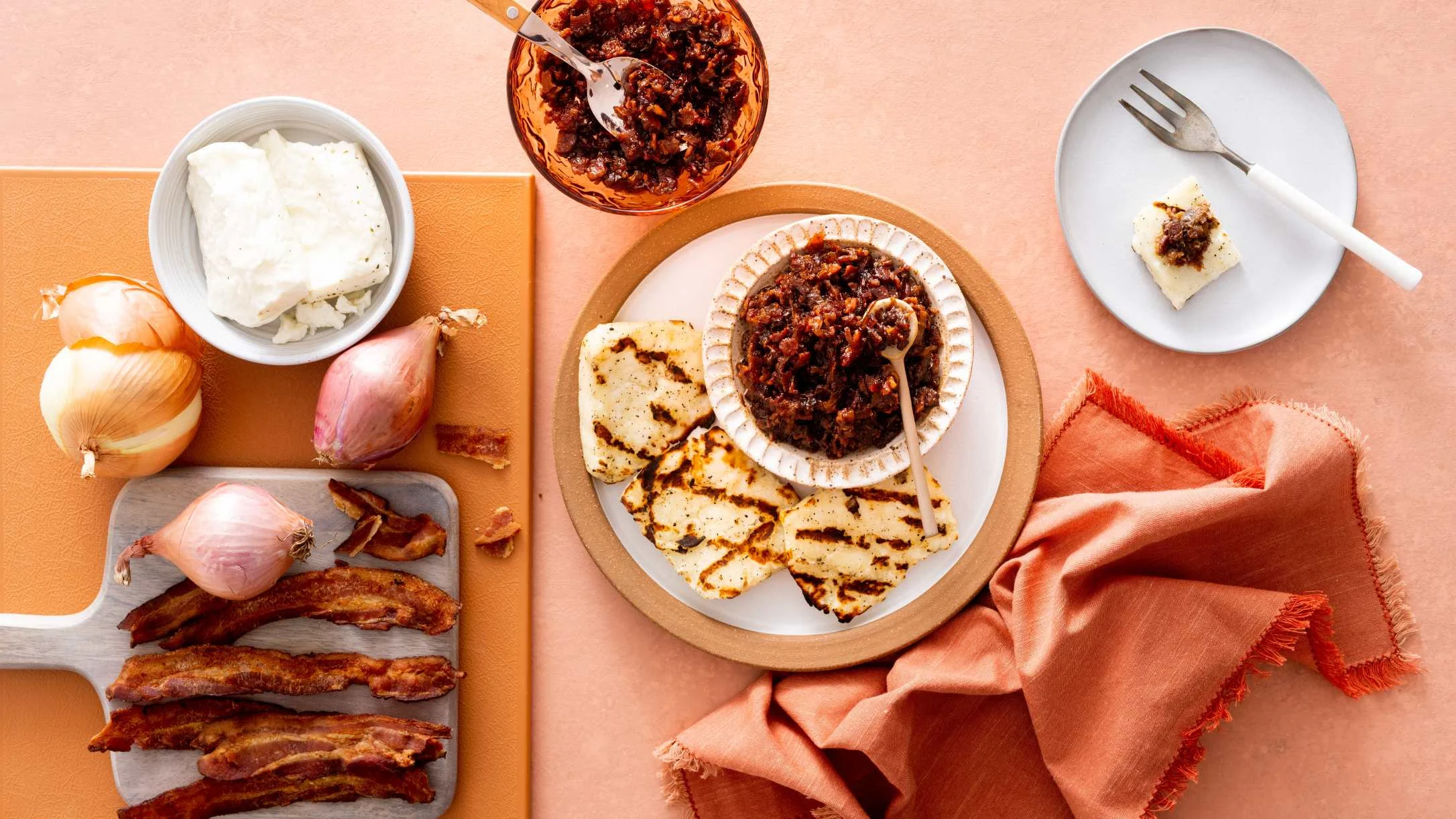 Bacon jam appetizer spread with grilled cheese, and onions on a peach-colored background.