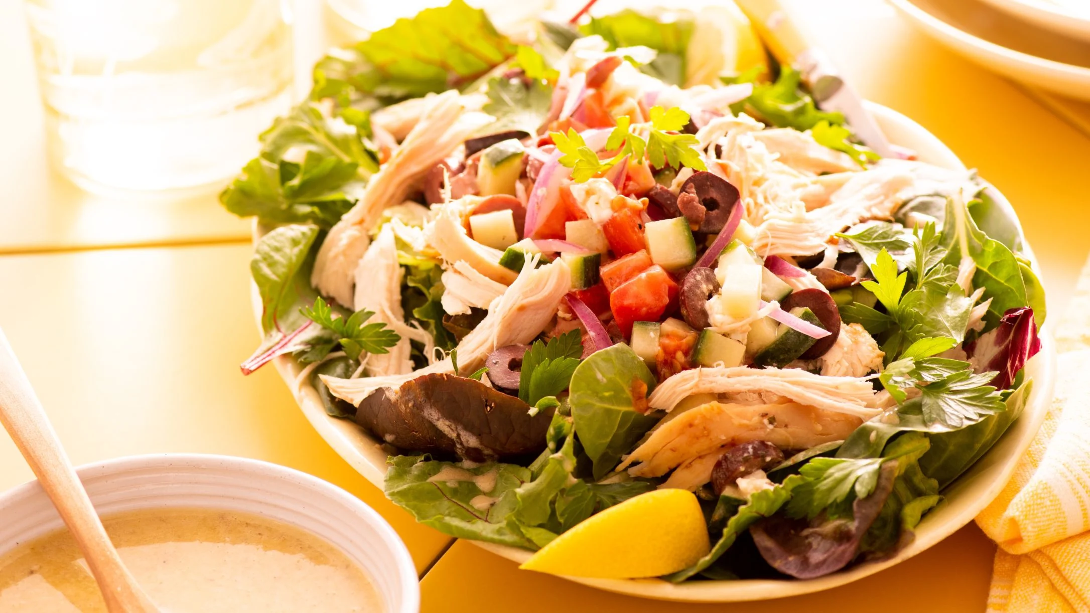 Fresh chicken salad with mixed greens, tomatoes, cucumbers, red onions and olives served with dressing on the side.